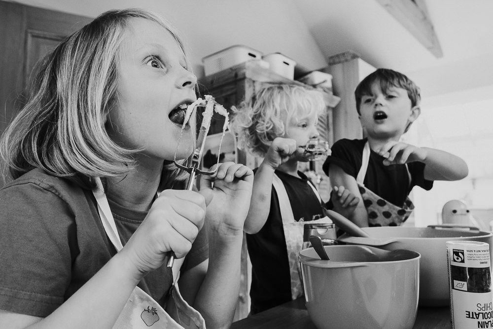 day in the life photographer children baking and licking cake mix from beaters black and white photo