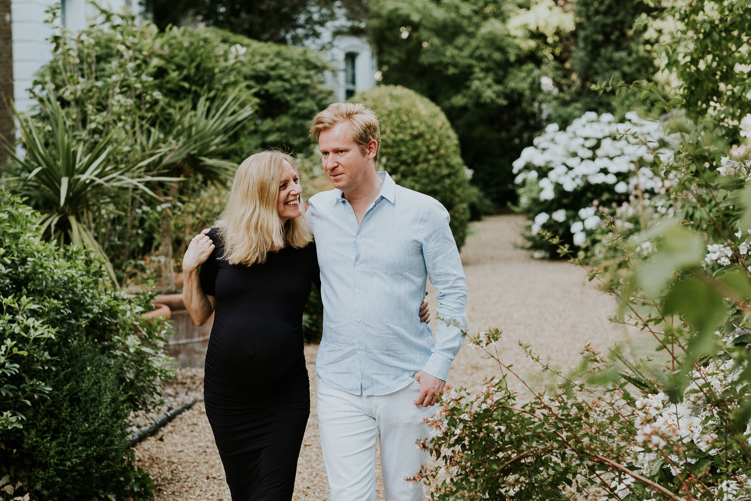 LONDON MATERNITY PHOTO SHOOT pregnant woman and husband walking in garden with flowers
