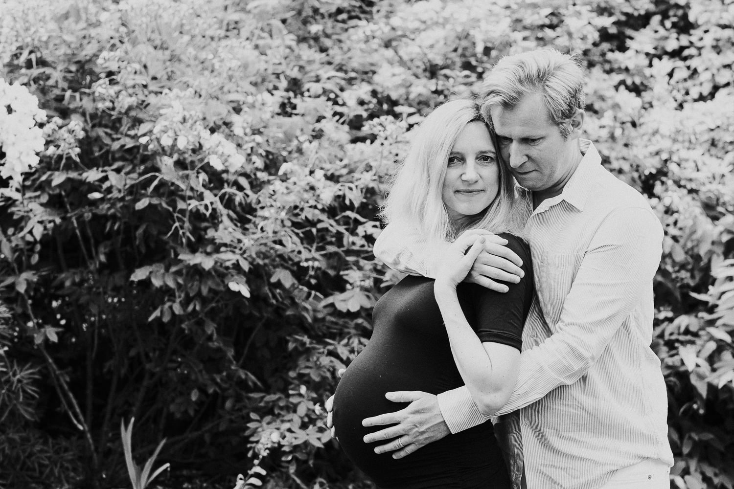 LONDON MATERNITY PHOTO SHOOT pregnant woman and husband hugging in garden black and white