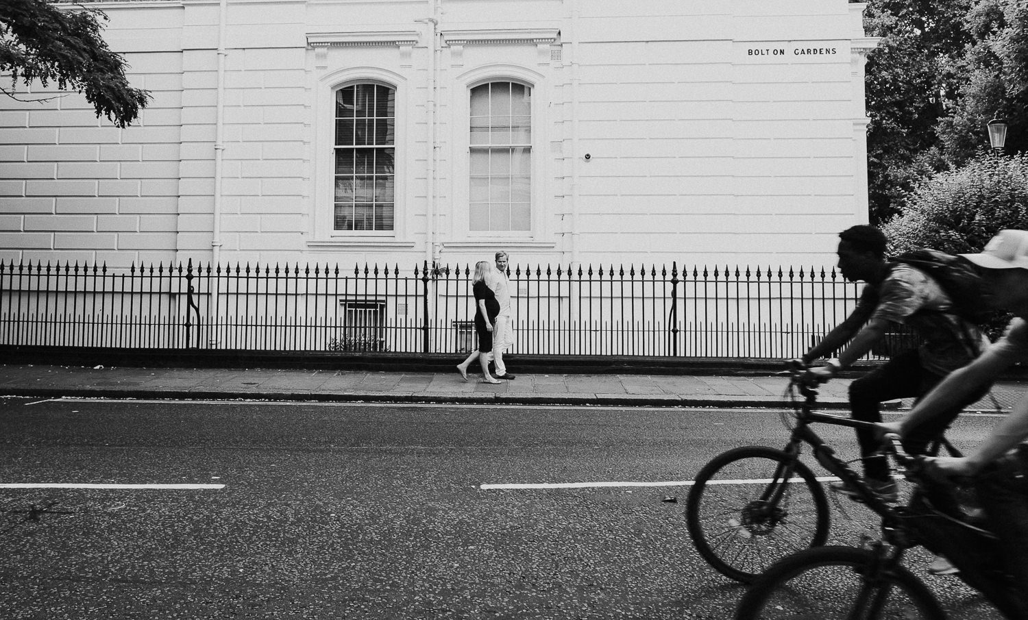 LONDON MATERNITY PHOTO SHOOT pregnant woman and husband walking on street in south kensington london with bicycles