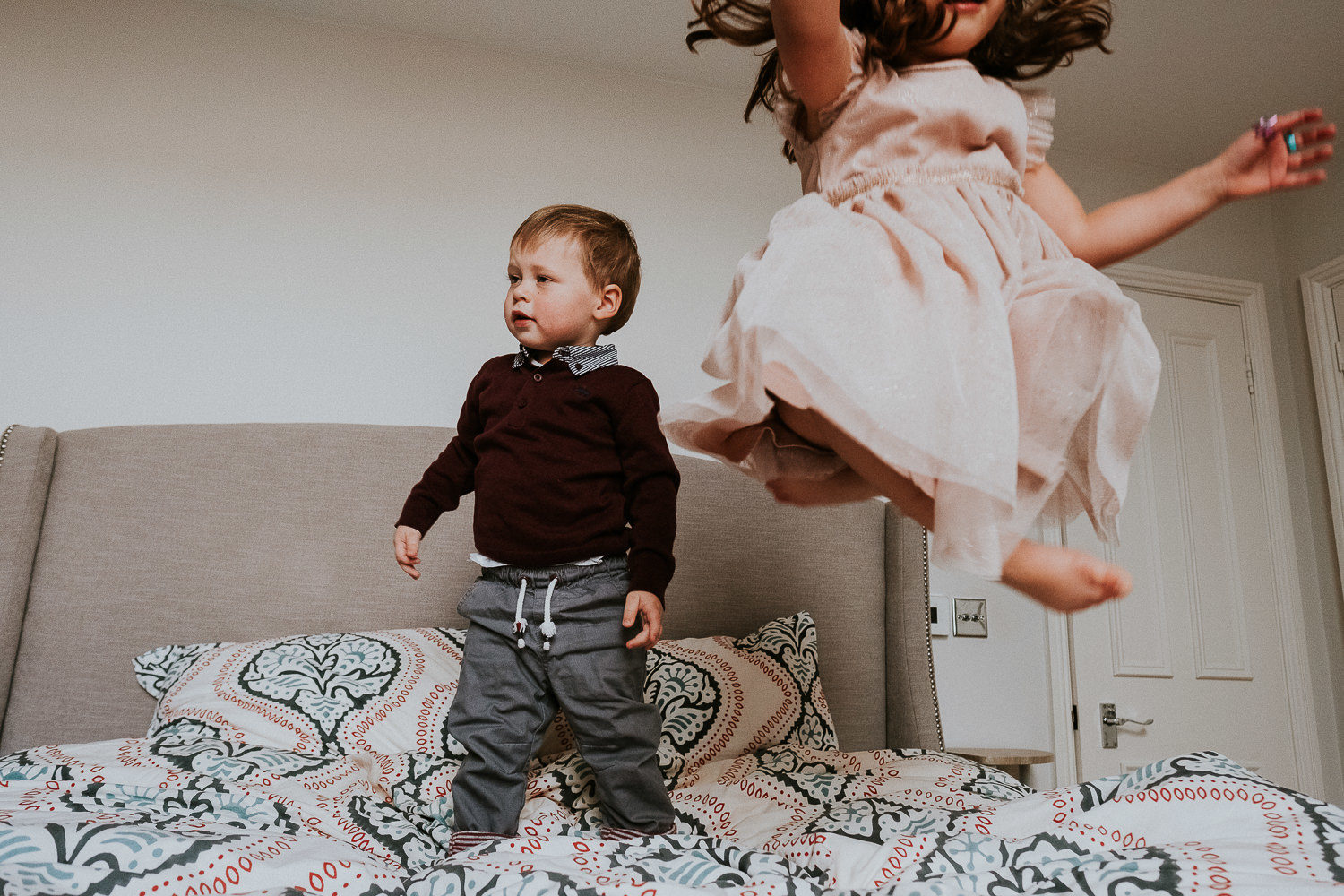 notting hill family photographer portrait of girl and brother bouncing on bed