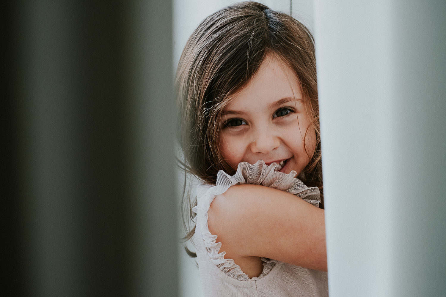 notting hill family photographer portrait of girl hiding behind curtain