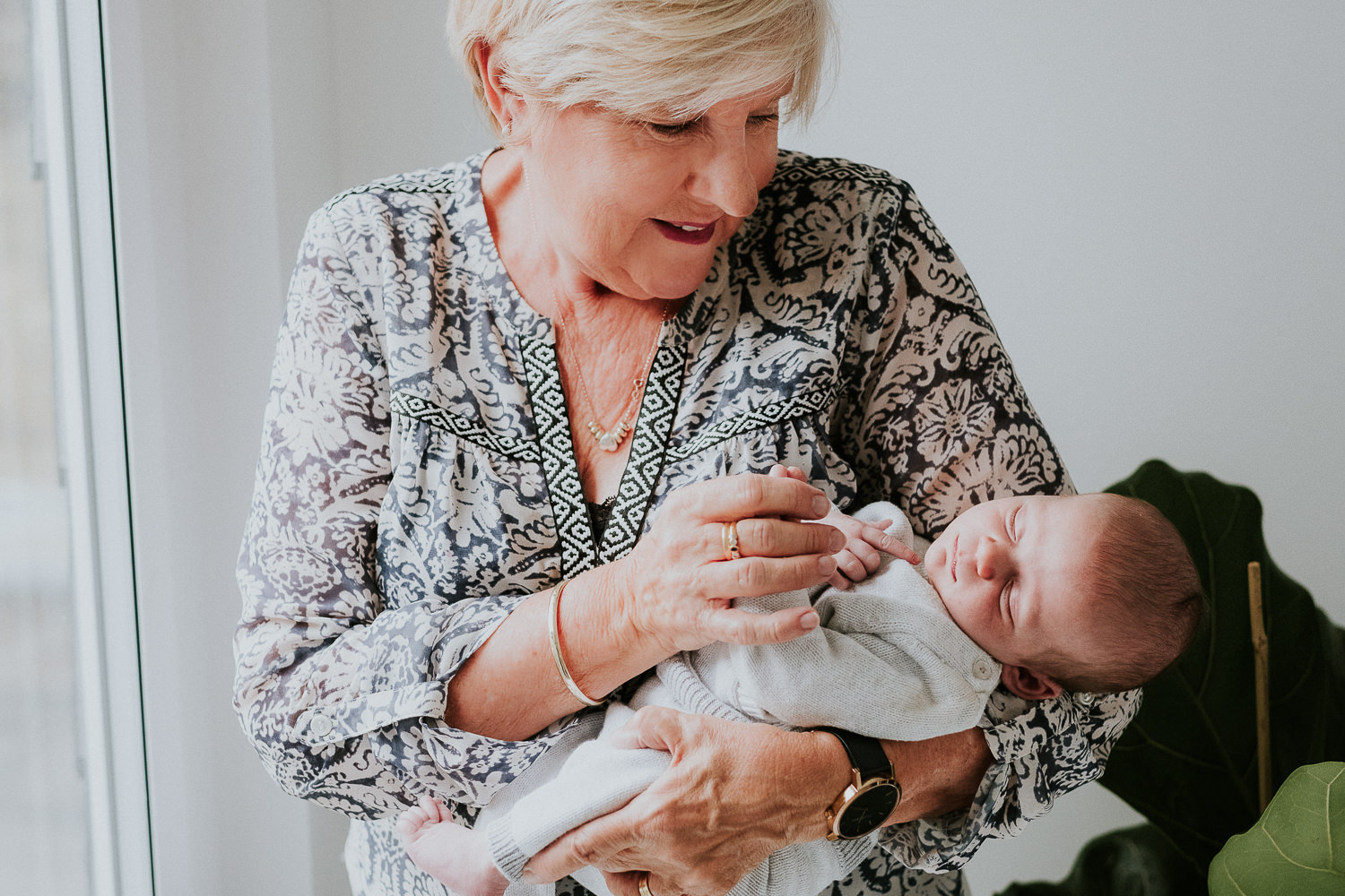 grandmother holding baby boy looking out of window