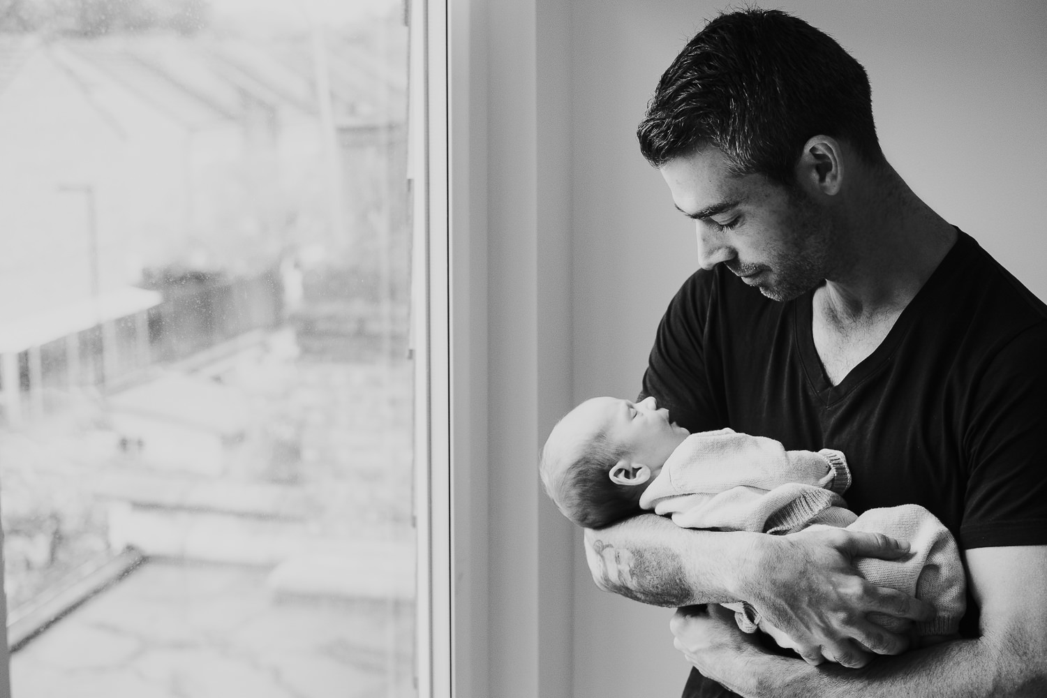 father holding baby son black and white photo london newborn photography