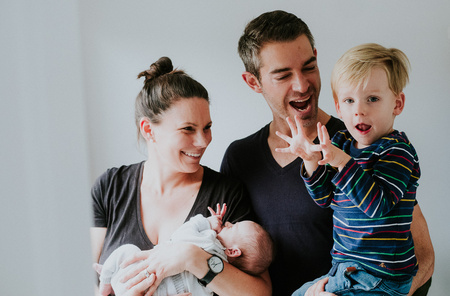 new parents and toddler holding baby son london newborn photography