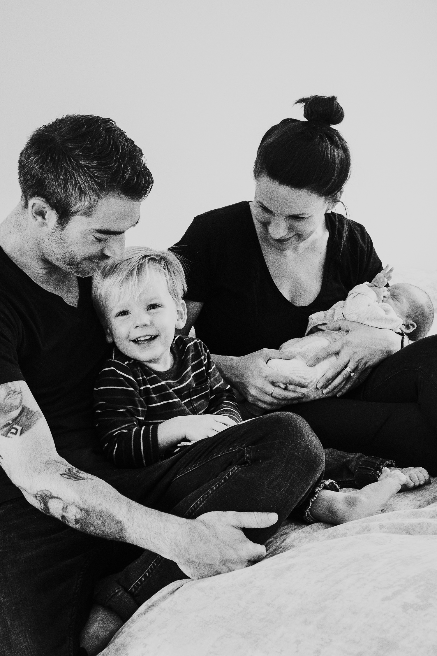 new parents and toddler holding baby son black and white photo london newborn photography