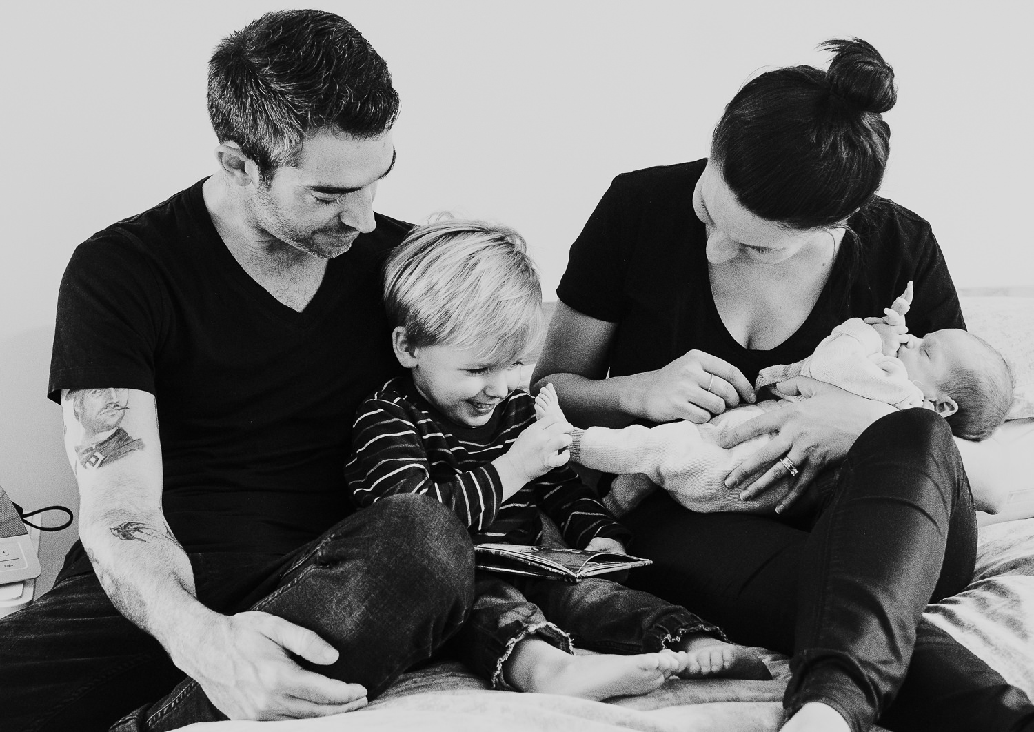 new parents and toddler holding baby son black and white photo london newborn photography
