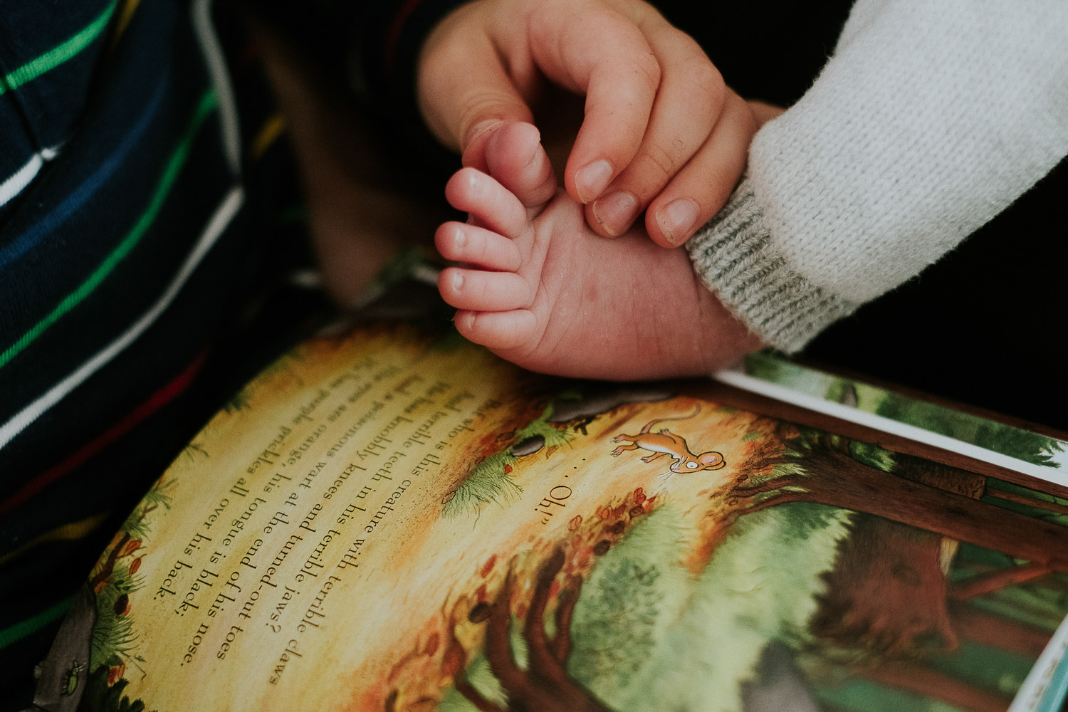toddler brother holding baby's foot london newborn photography