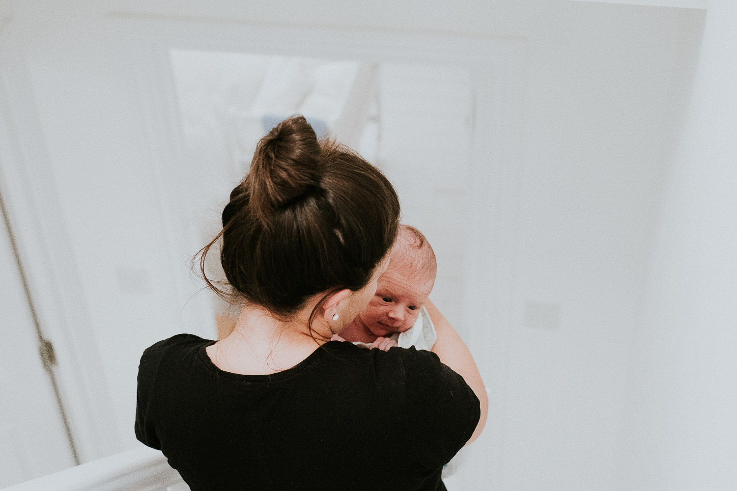newborn baby boy being carried downstairs in mothers arms