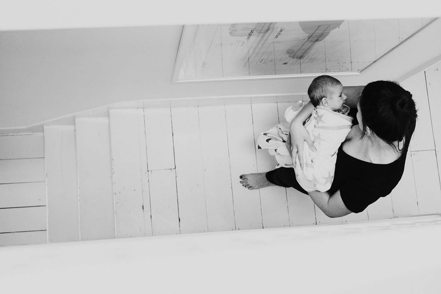 newborn baby boy being carried downstairs in mothers arms black and white photo