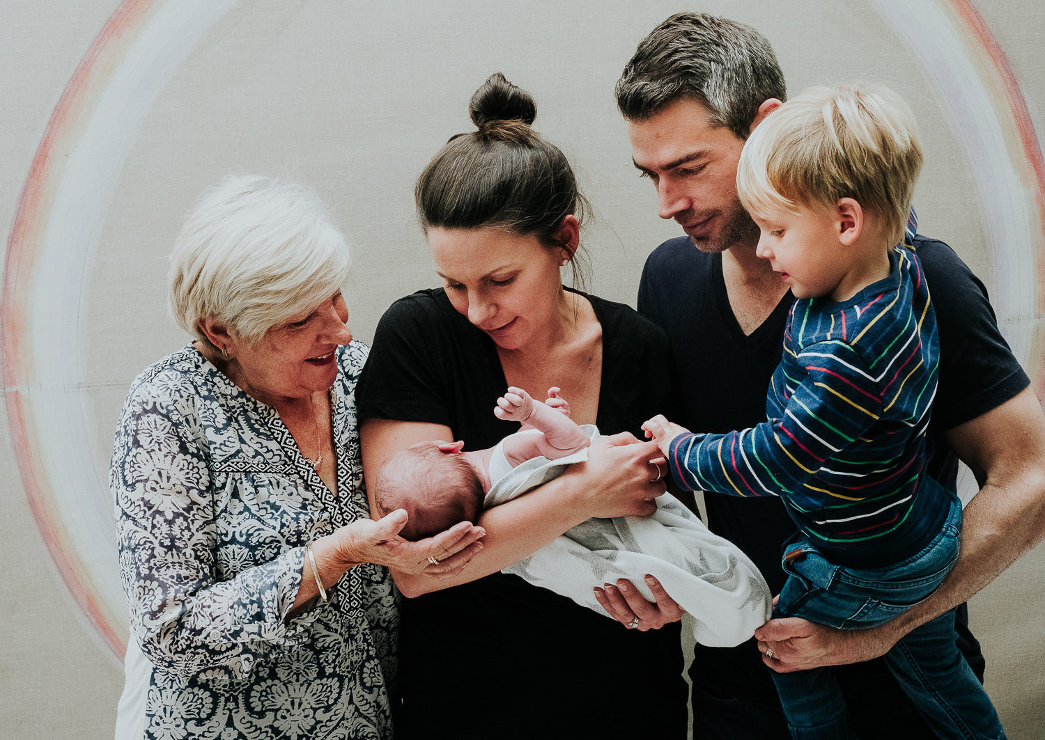 three generation family grandparents with newborn baby and toddler brother in front of artwork in london home