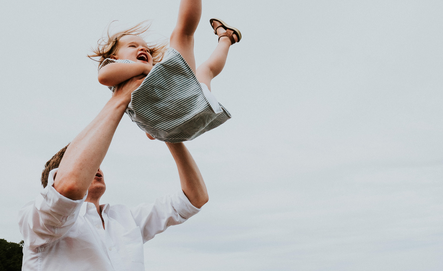 DAD THROWING DAUGHTER IN AIR ON BEACH LAUGHING WHITSTABLE FAMILY PHOTOGRAPHER