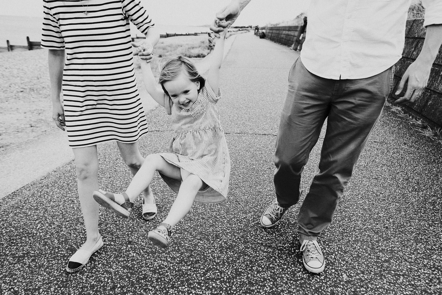 WHITSTABLE FAMILY PHOTOGRAPHER TANKERTON SLOPES FAMILY SHOOT FAMILY SWINGING CHILD ON BEACH