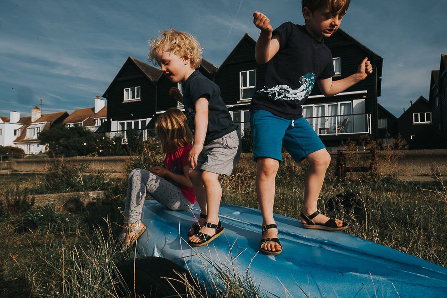 5 reasons you shouldn't wear matching outfits for your family photos. Three young children playing on overturned boat.