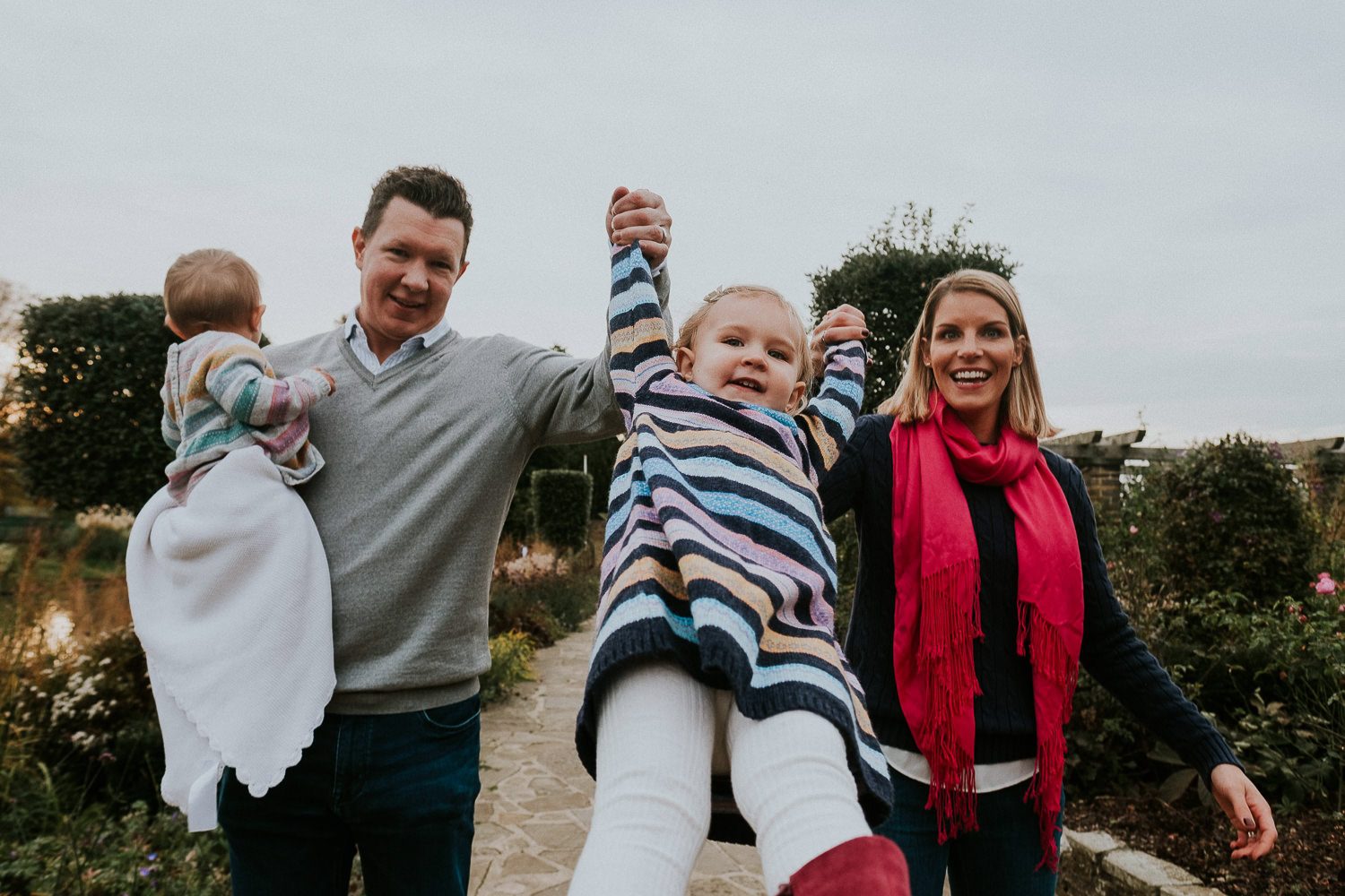 Parents swinging toddler by her arms.