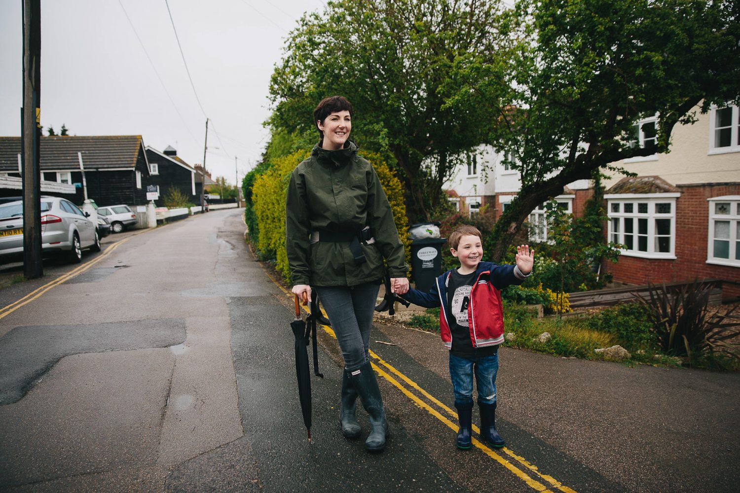 Mum walking holding son's hand on a rainy day