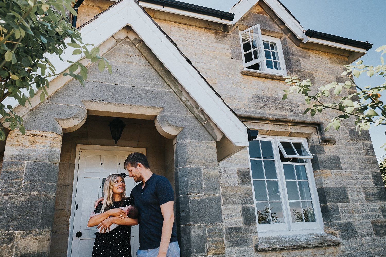 New parents with baby at front door of home
