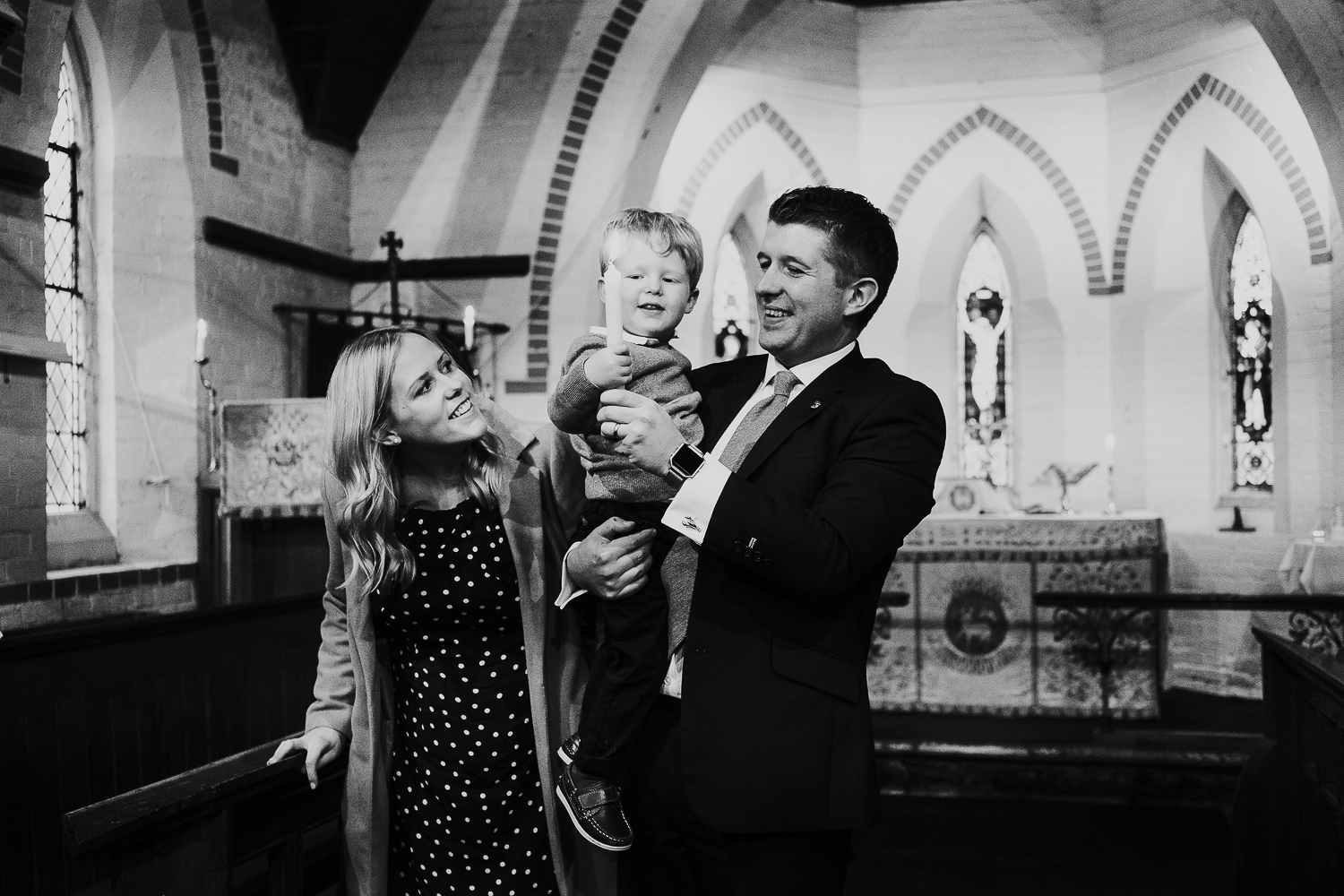 black and white photo of boy lighting candle at christening