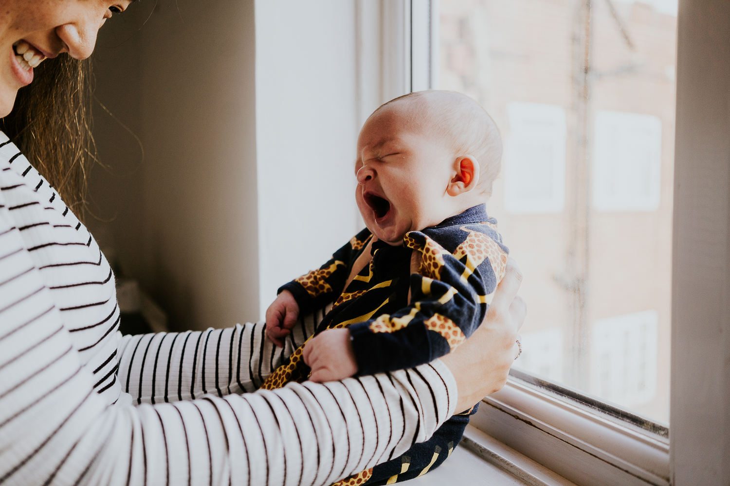newborn baby yawning sat in window