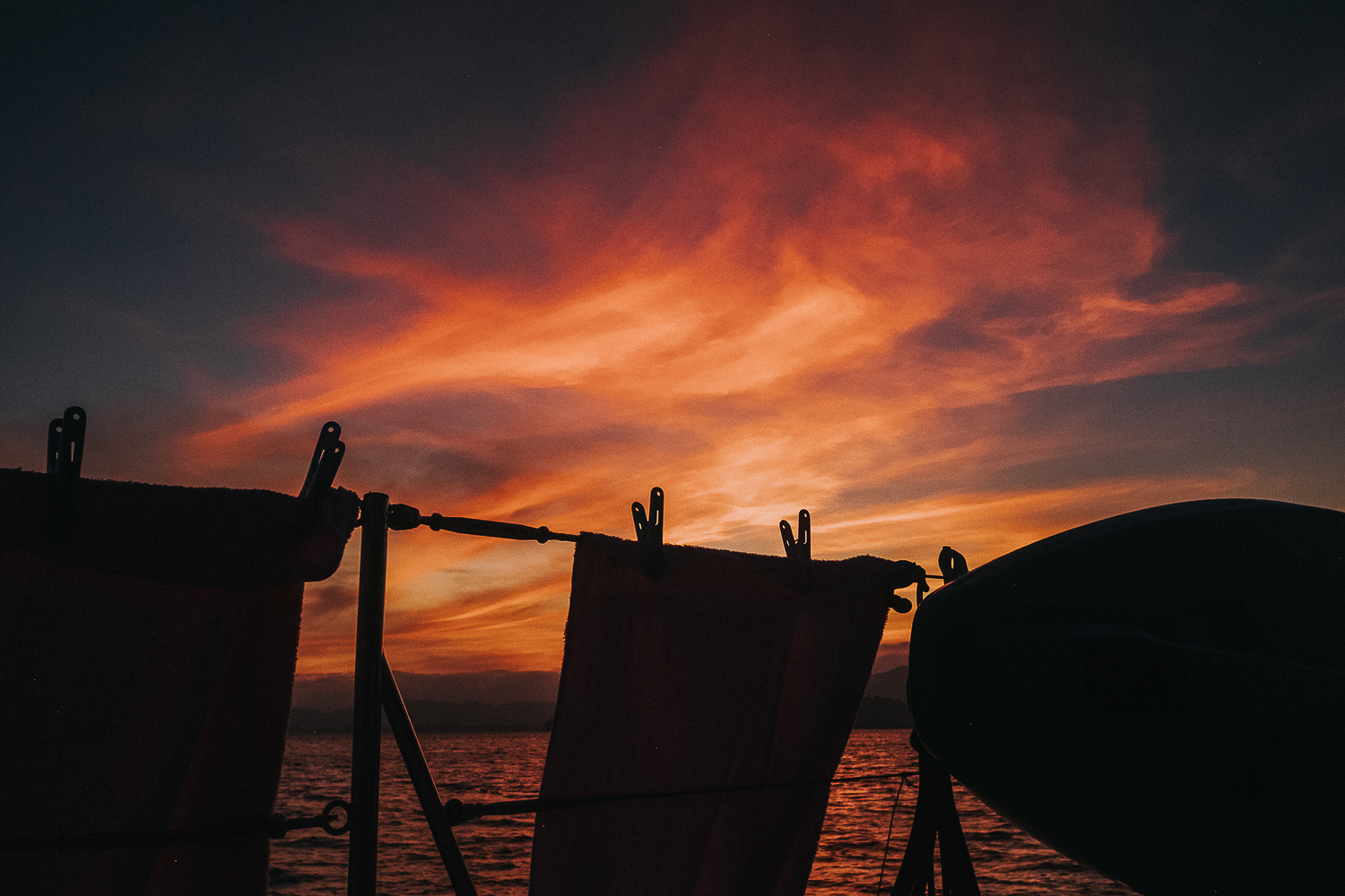 Thailand sunset shilhouette of towels on boat in front of orange sky