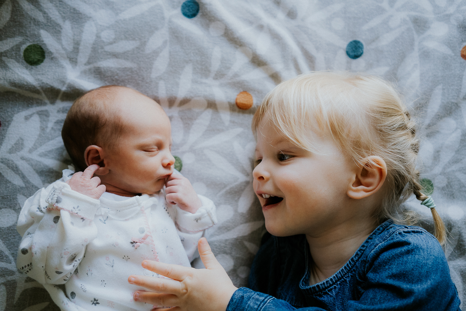 London family photography 2020 older sister and baby on bed