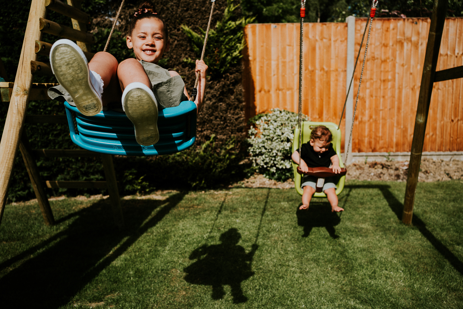 London family photography 2020 siblings on swings in garden in the sunshine