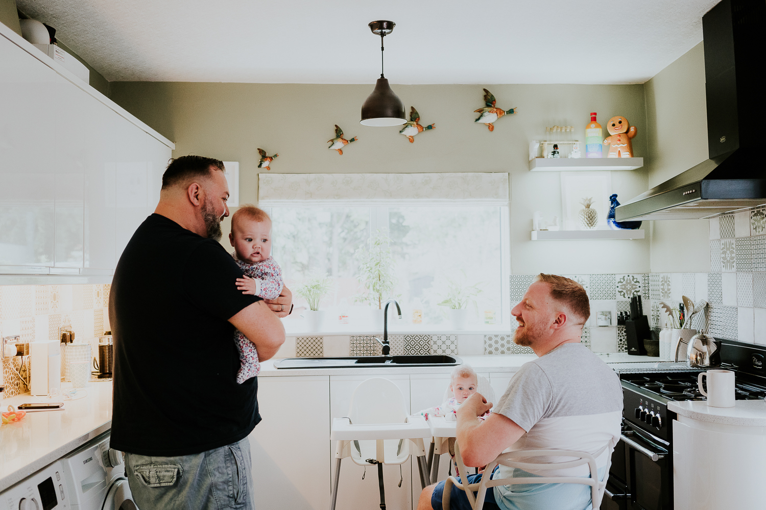 day in the life photo shoot two dads with baby twin girls in kitchen family scene