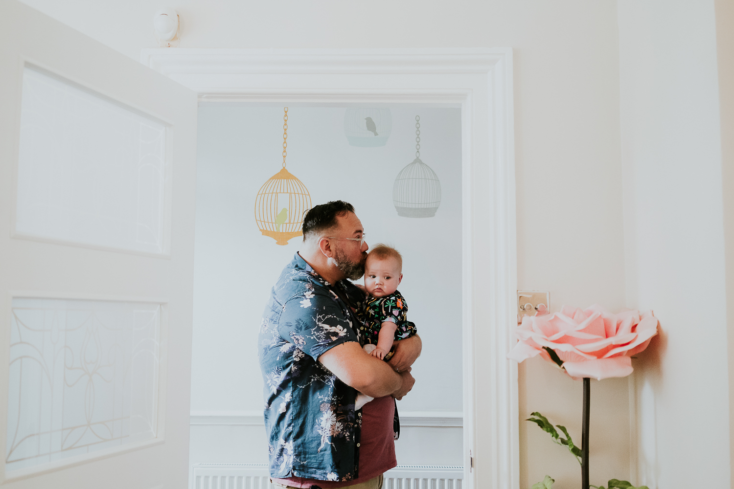 day in the life photo shoot father holding baby daughter in hallway kissing her on the head