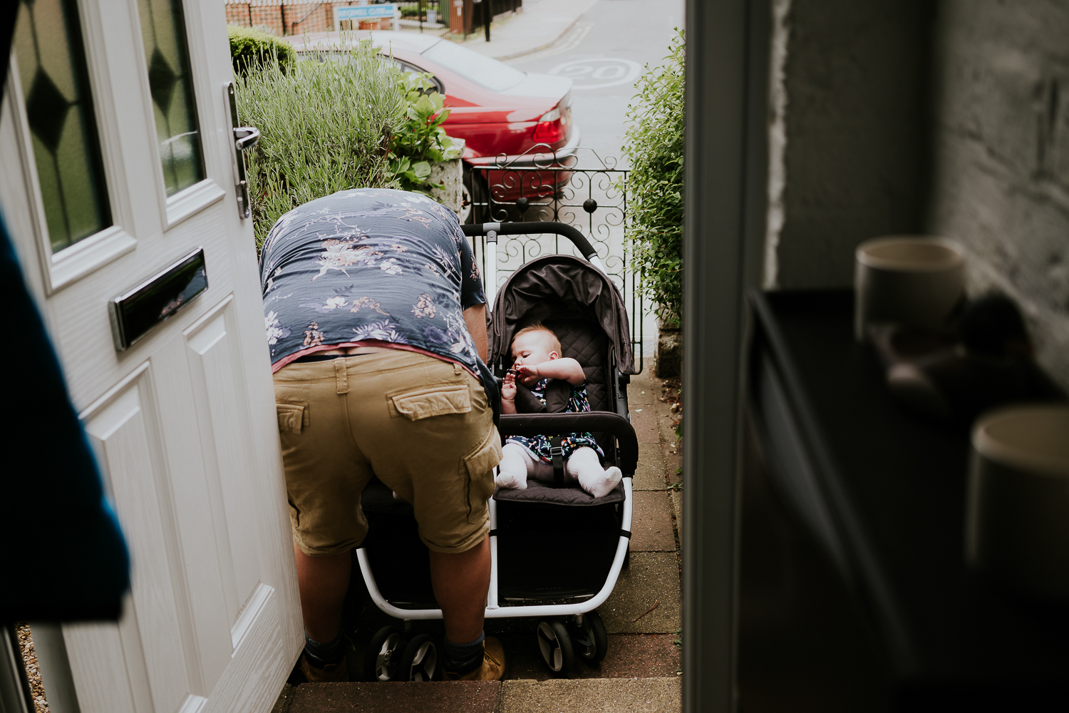 day in the life photo shoot father strapping twin baby girls into double pushchair