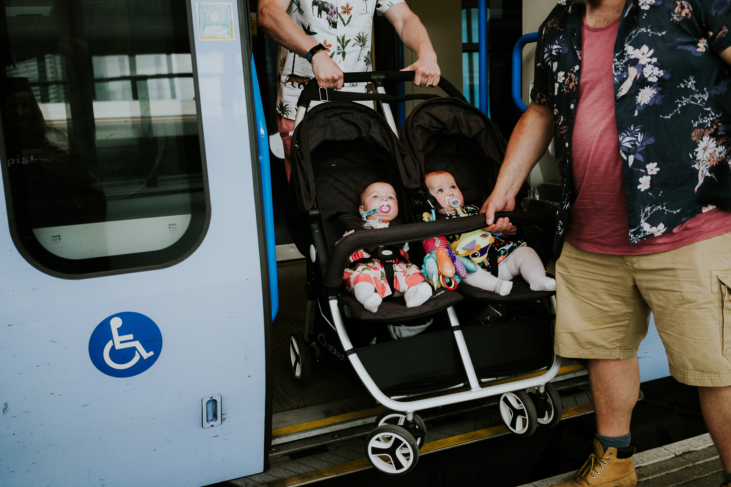 day in the life photo shoot two fathers and twin baby girls in double buggy getting off train