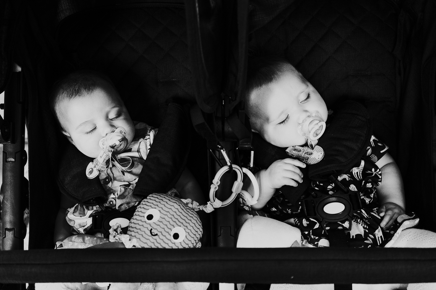 day in the life photo shoot twin baby girls asleep in double pushchair with dummies black and white shot