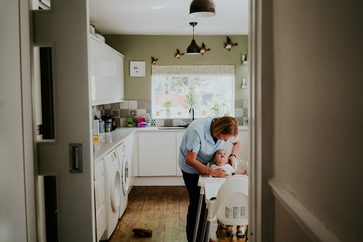 day in the life photo shoot kitchen scene with older woman strapping baby into a highchair