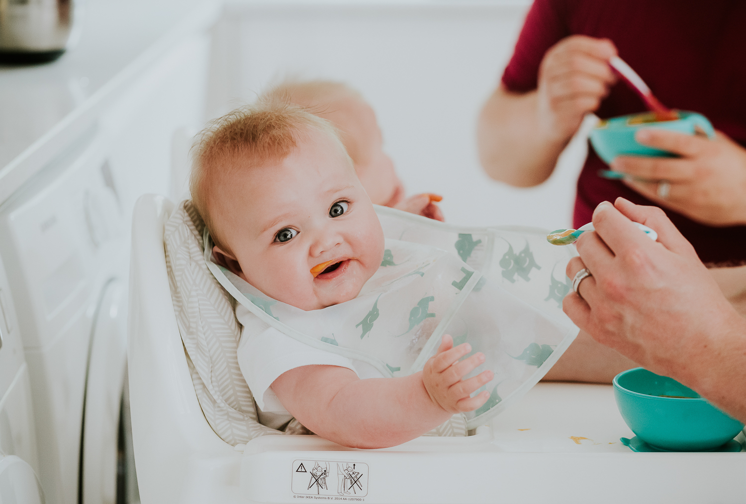 day in the life photo shoot baby in a highchair being spoon fed with food round her mouth
