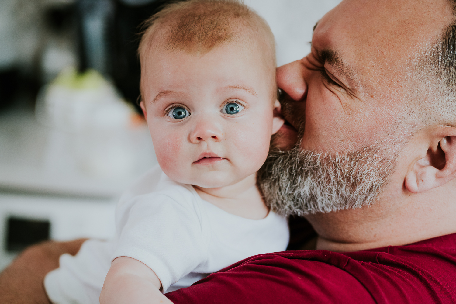 day in the life photo shoot father biting playfully on baby girls ear close up with beard