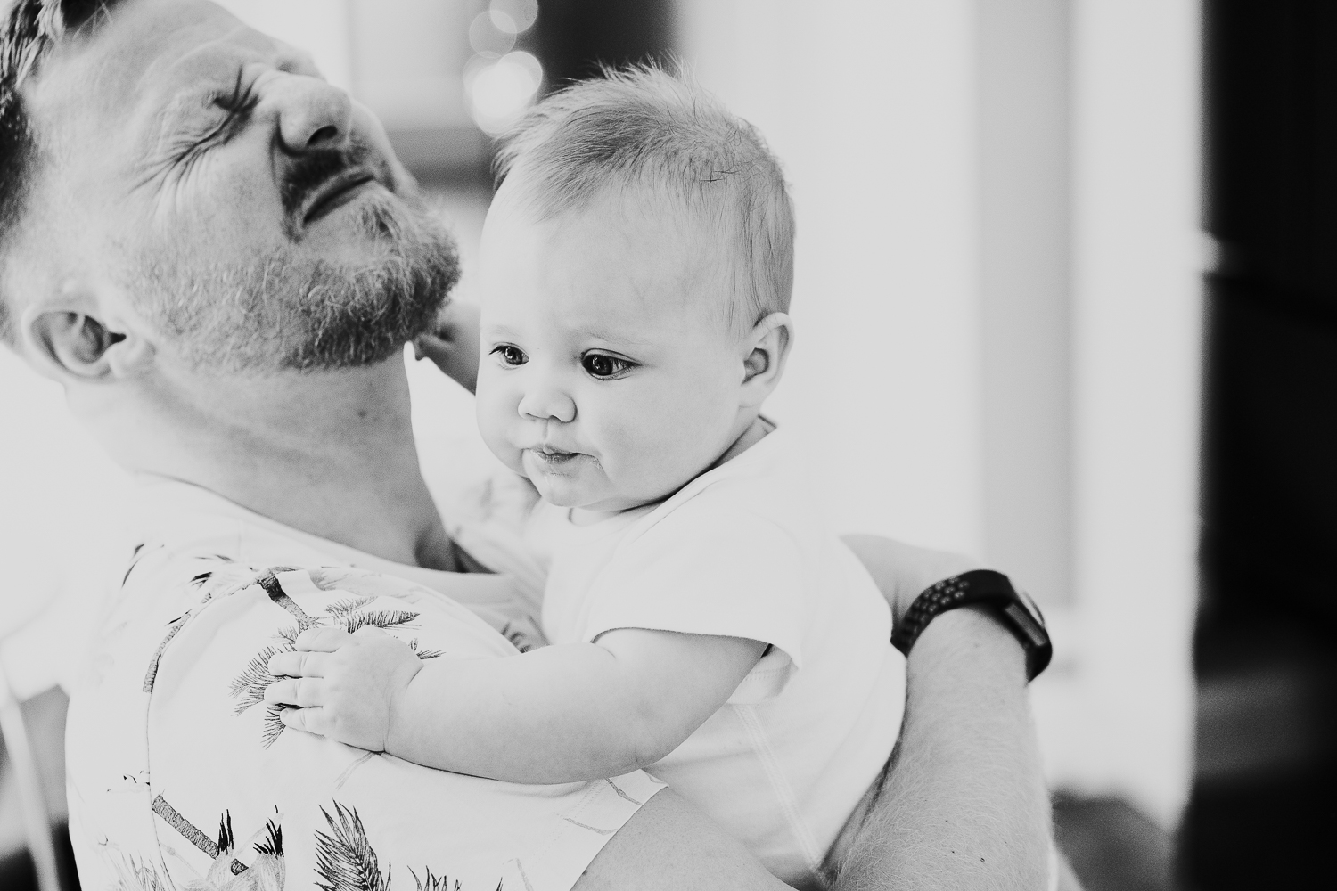 day in the life photo shoot close up of baby girl pulling on father's beard grimace expression black and white photo