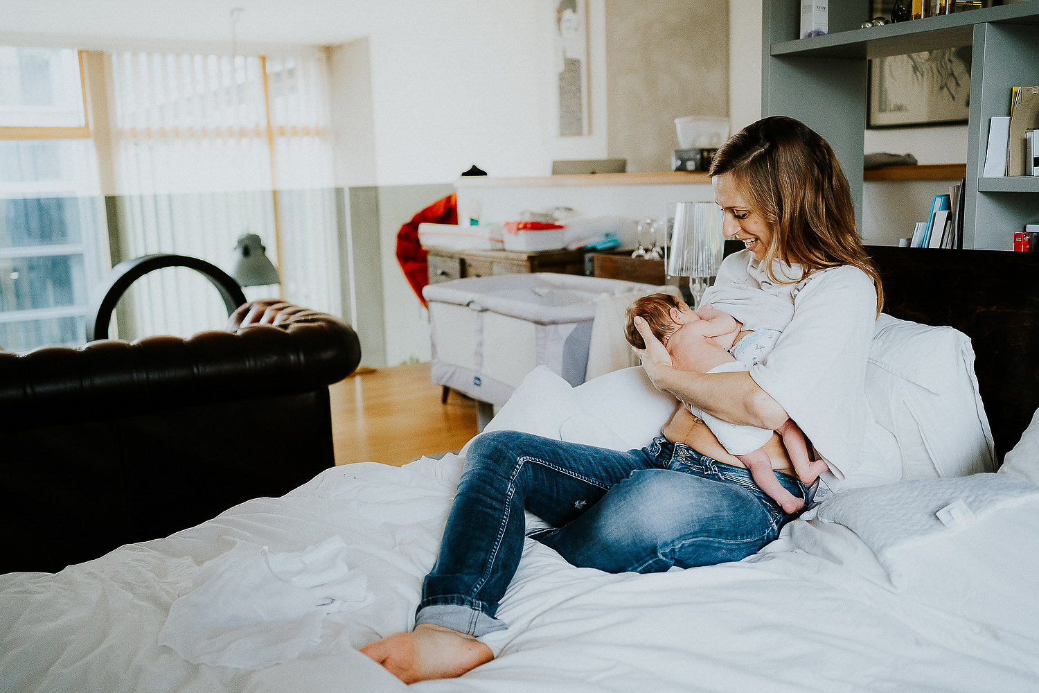 mother breastfeeding baby on bed at home london newborn baby photographer
