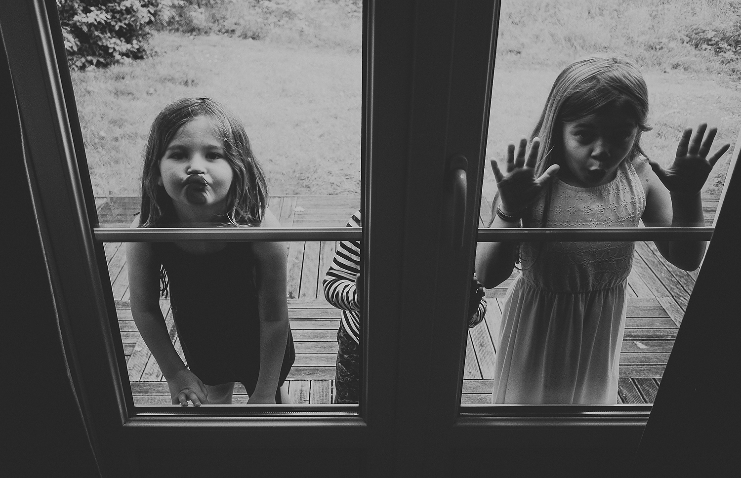 TWO CHILDREN PRESSING FACES ON WINDOW GLASS FAMILY PHOTOGRAPHY AT CENTER PARCS FRANCE LAC D'AILETTE