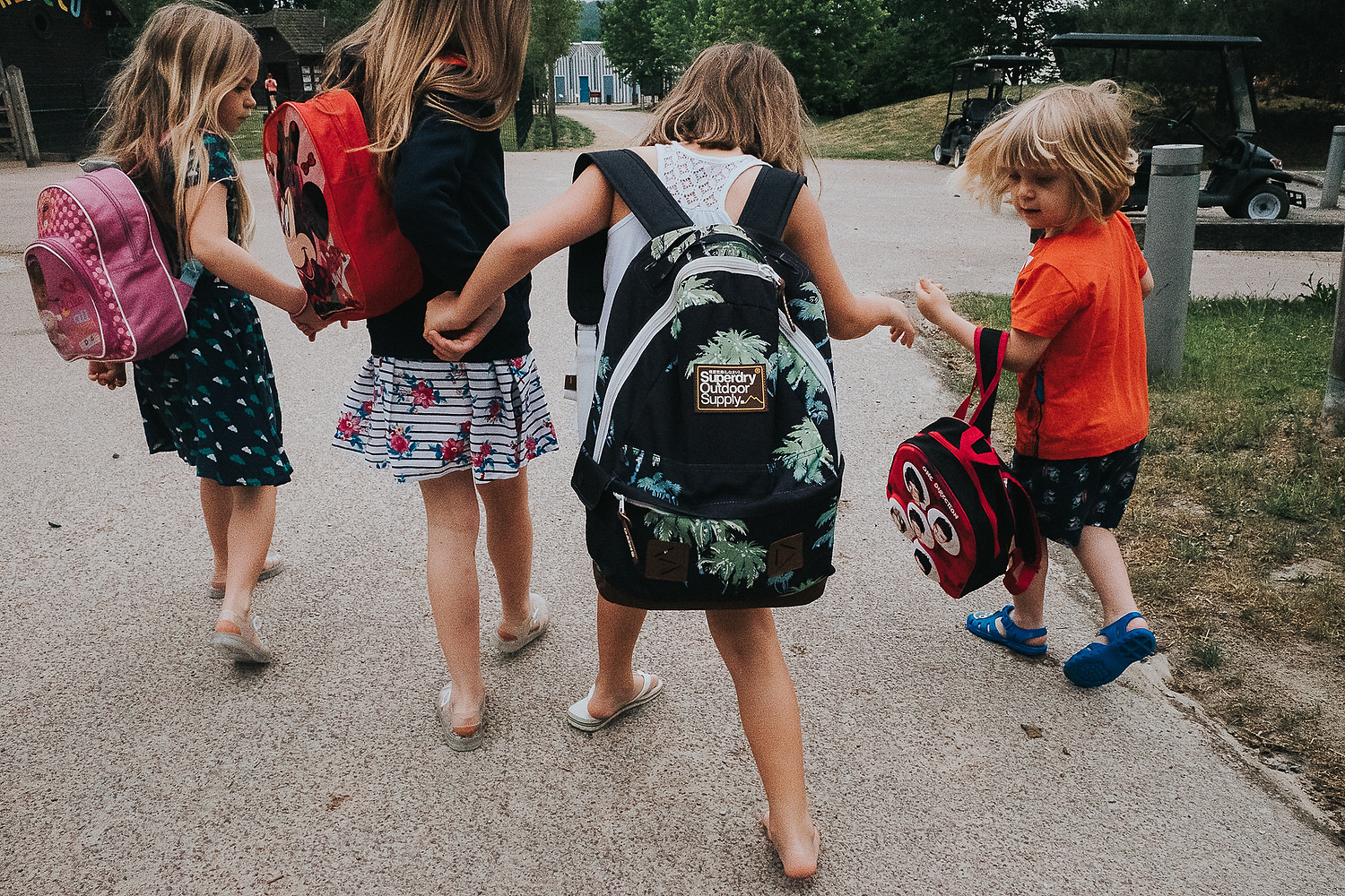 GROUP OF CHILDREN WALKING HAND IN HAND FROM BEHIND WITH RUCKSACKS FAMILY PHOTOGRAPHY AT CENTER PARCS FRANCE LAC D'AILETTE