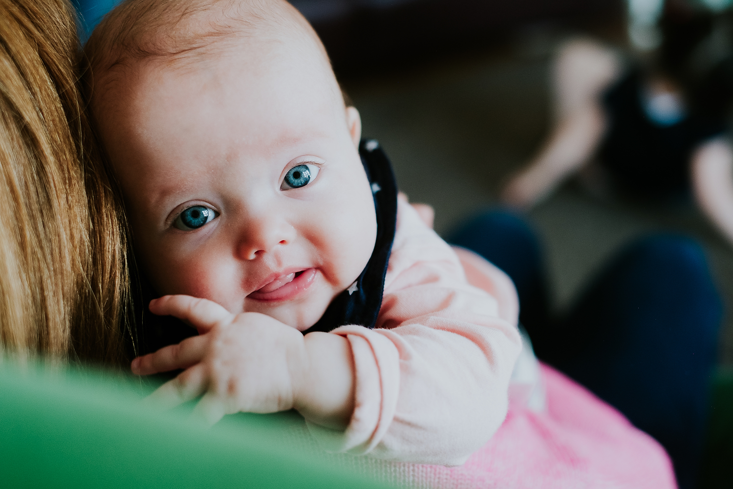 mother cuddling baby on green chair at home islington family photographer