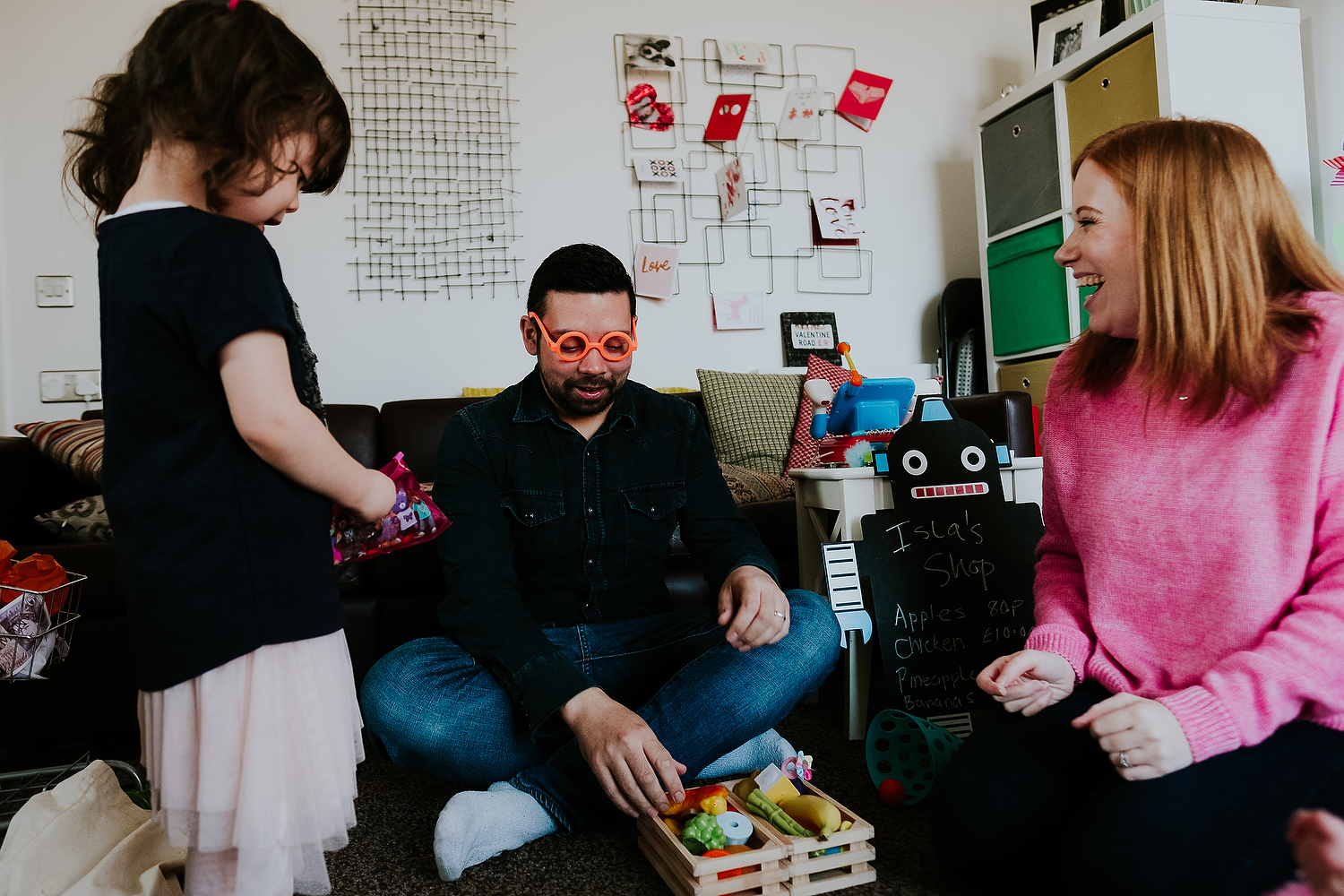 family playing make believe at home with toddler daughter dad wearing silly orange toy glasses islington family photographer