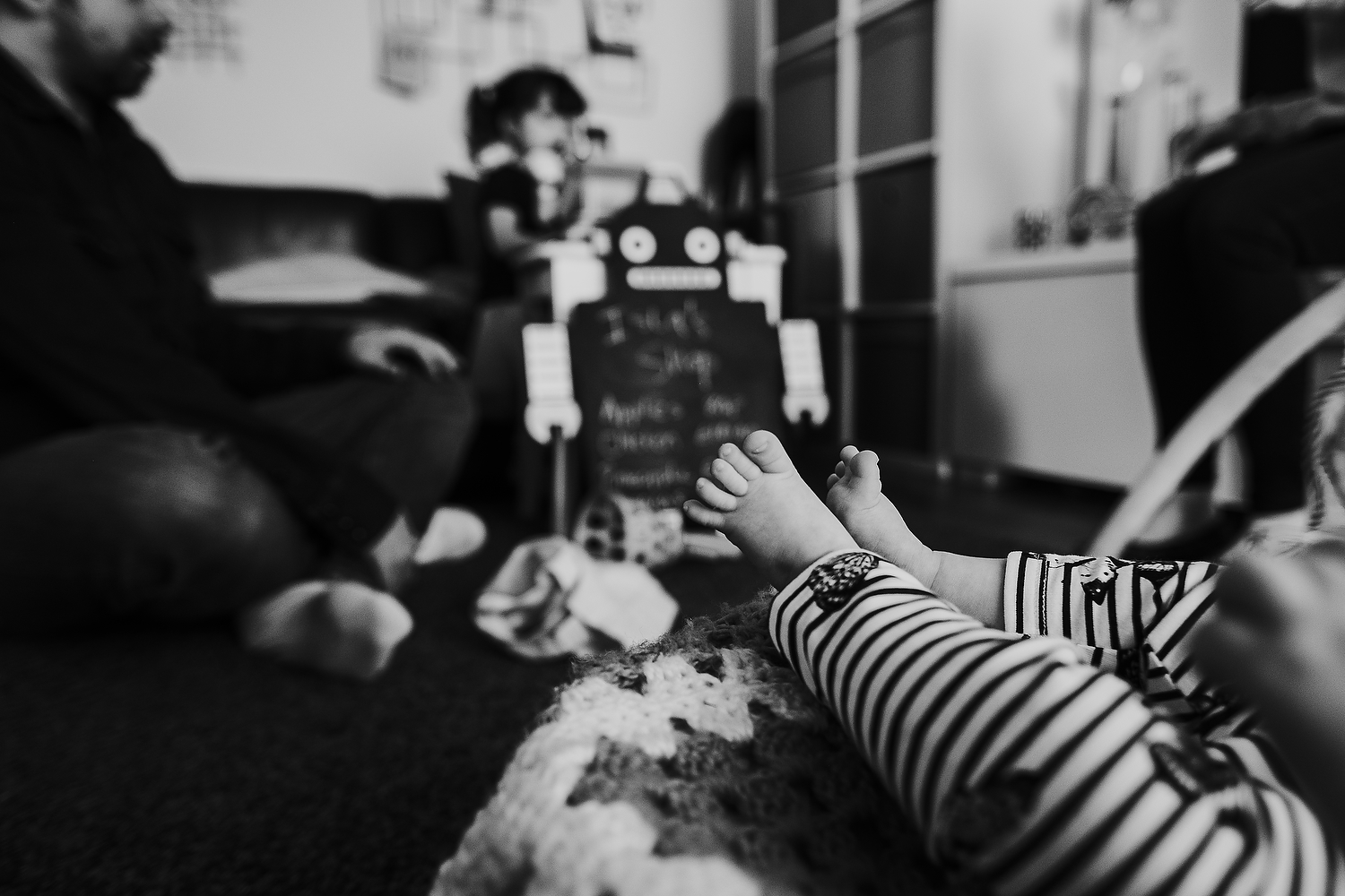 close up baby toes with family playing in background islington family photographer