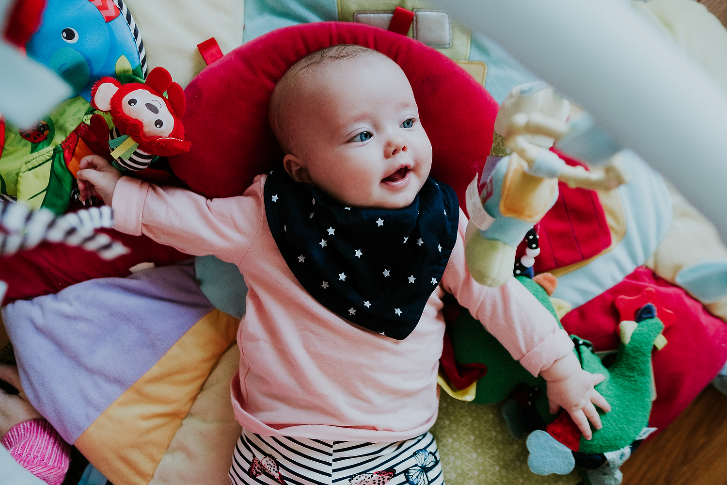 islington family photographer aerial shot of baby lying on colourful play mat smiling