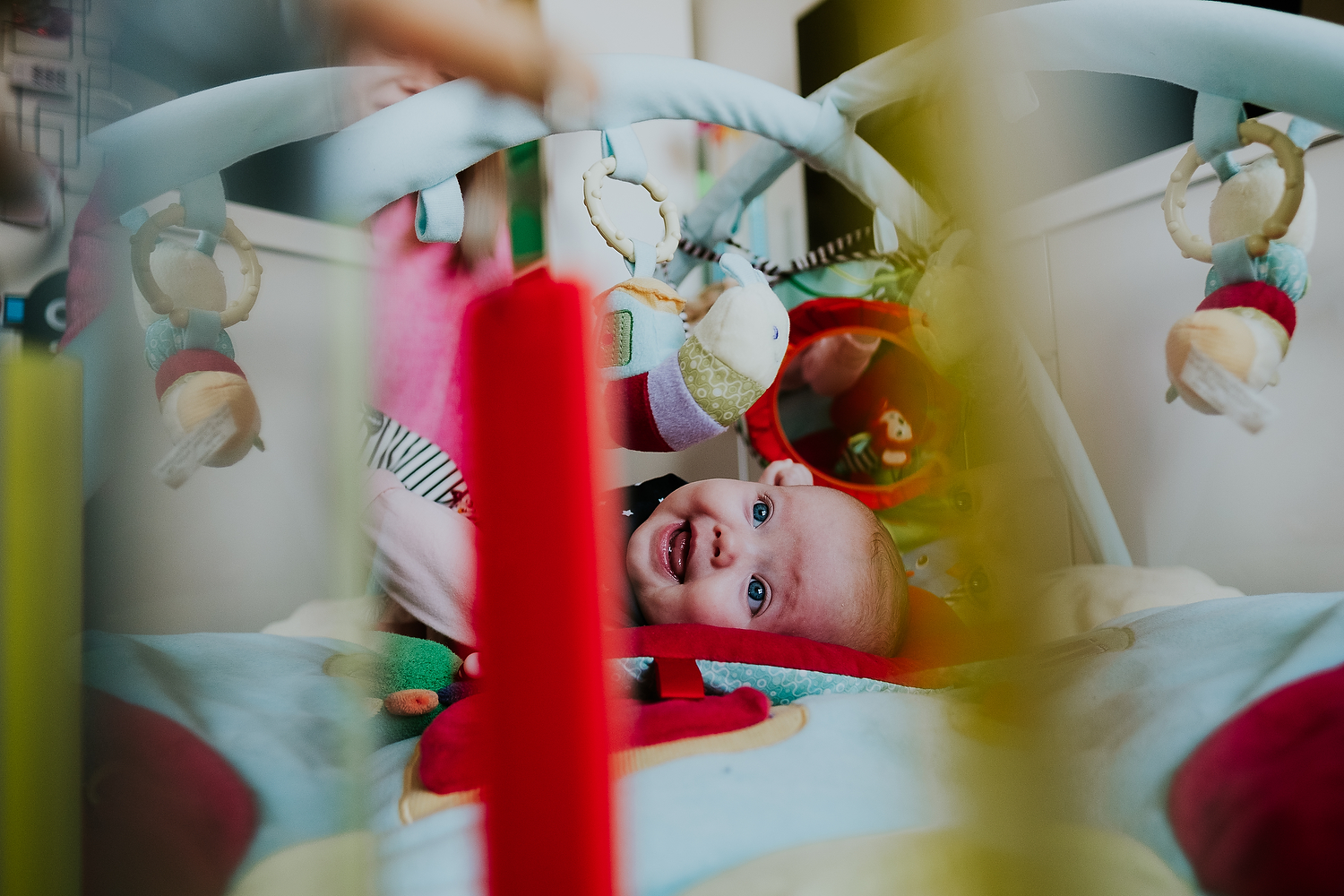 islington family photographer shot of baby lying on colourful play mat smiling