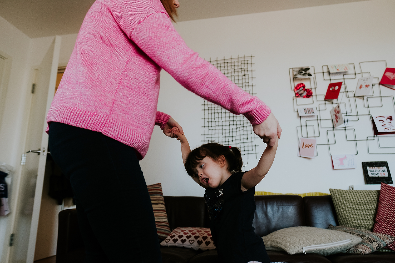 islington family photographer mother and toddler daughter dancing in living room at home