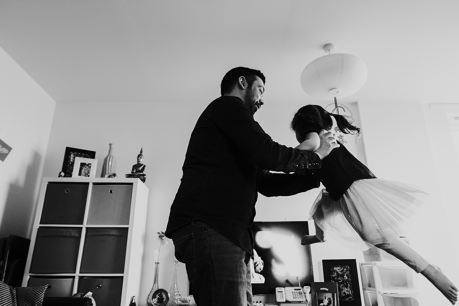 islington family photographer dad and toddler daughter dancing in living room at home with dirty dancing movie on tv in background