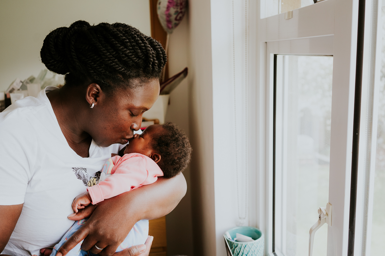 woman of colour with baby daughter next to window