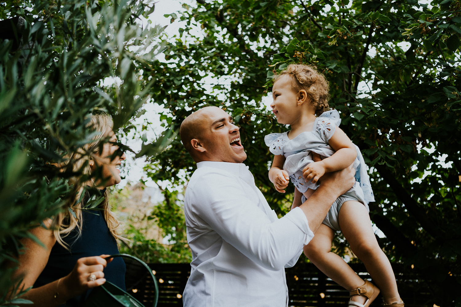 parents swinging toddler daughter and laughing NORTH KENSINGTON FAMILY PHOTO SESSION