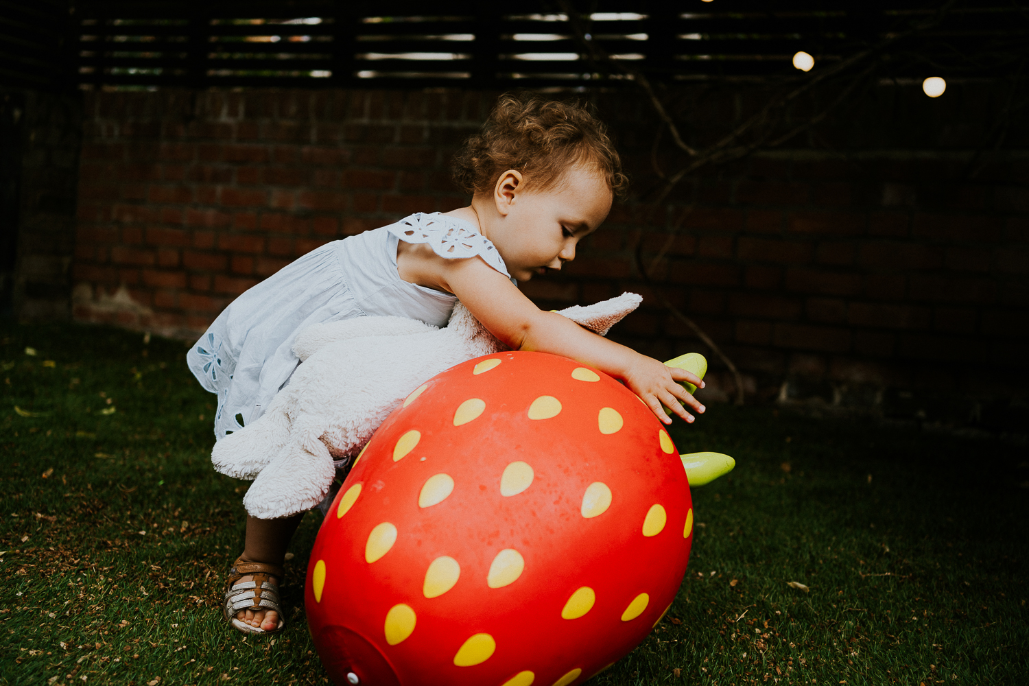 toddler girl playing with giant strawberry toy in garden NORTH KENSINGTON FAMILY PHOTO SESSION