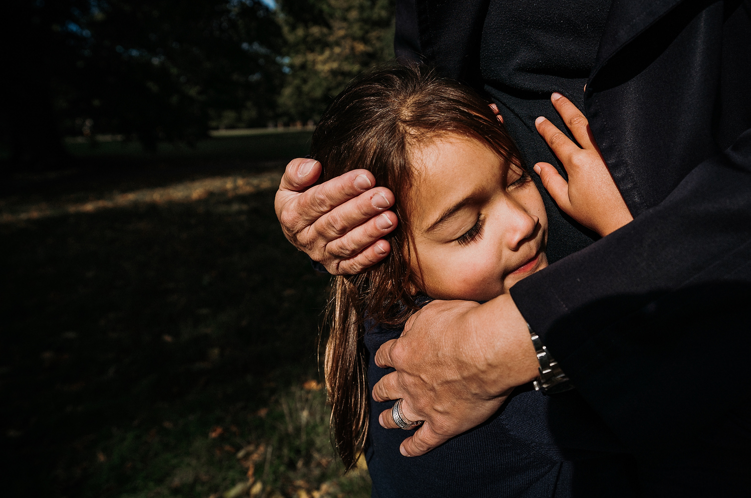 BOOKING A FAMILY PHOTO SESSION CLOSE UP CHILD'S DAUGHTER HEAD BEING HELD IN EMBRACE BY MOTHER