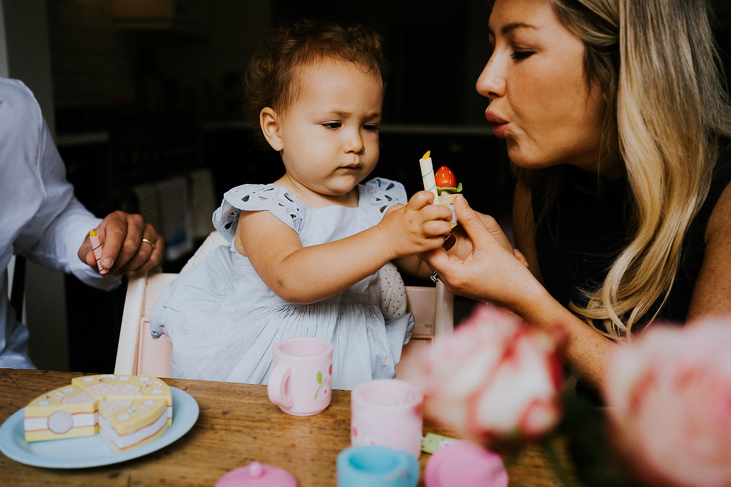 BOOKING A FAMILY PHOTO SESSION LITTLE GIRL AND MUM BLOWING OUT A PRETEND CANDLE ON A CAKE SHAPED TOY